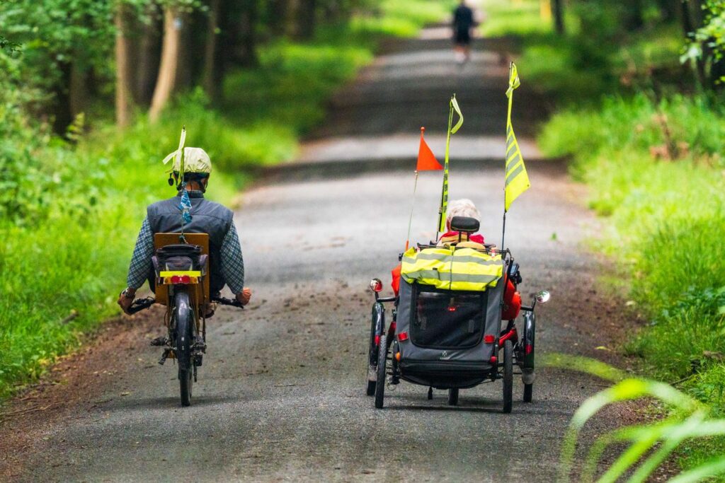 Twee oudere mensen fietsen op een bospad op een zomerse dag