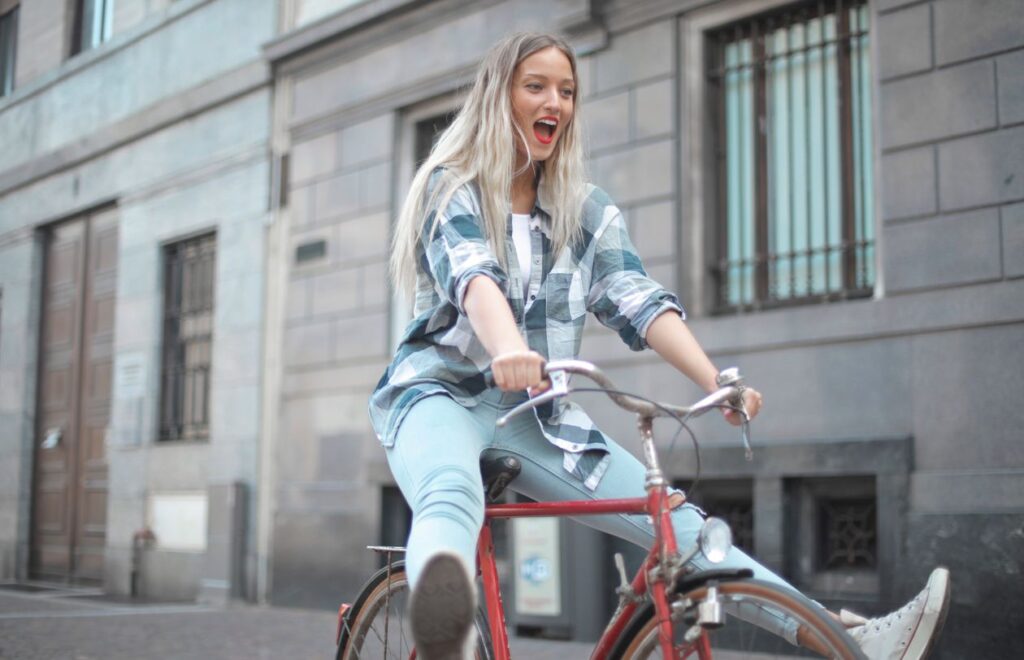 Lachende vrouw fietst op een rode fiets door een straat